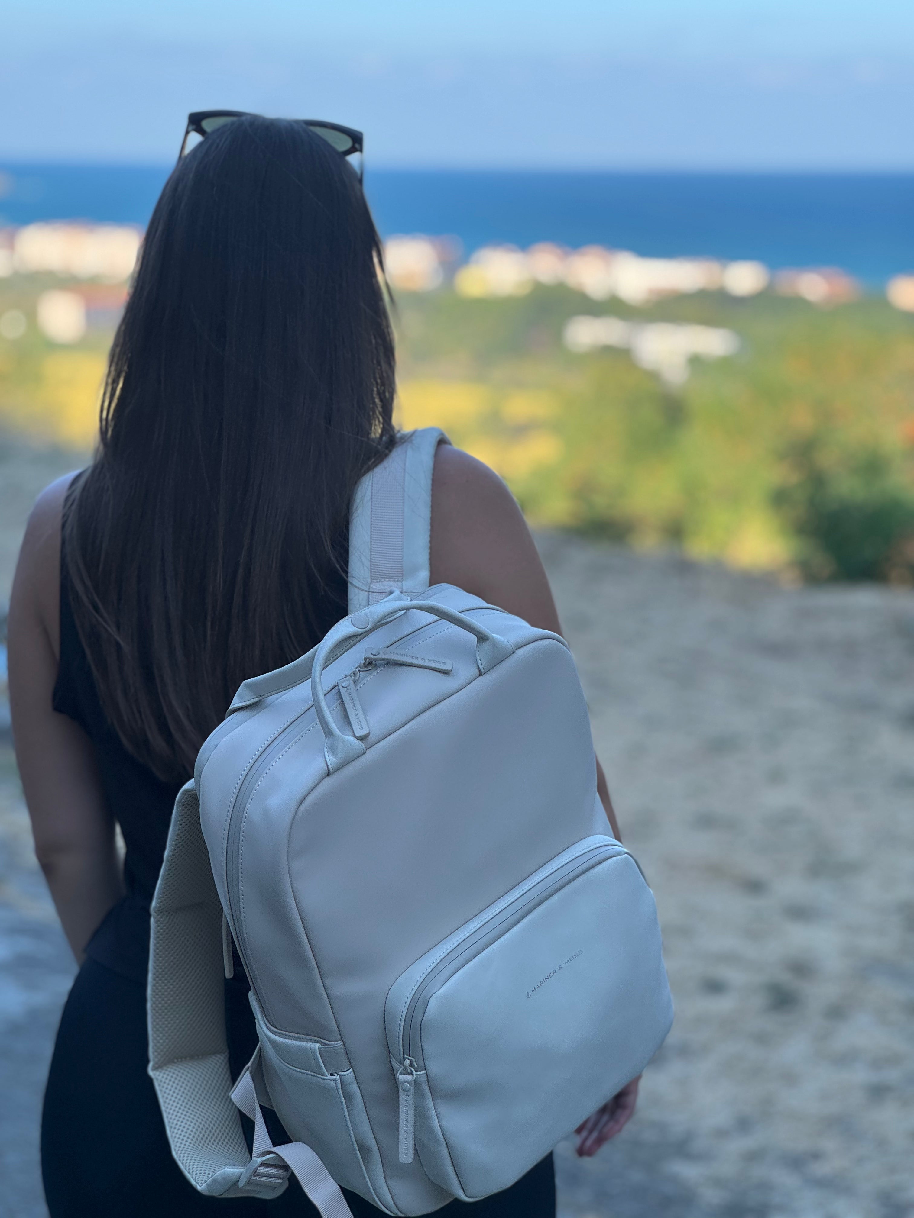Person with a beige backpack standing on a beach with ocean view