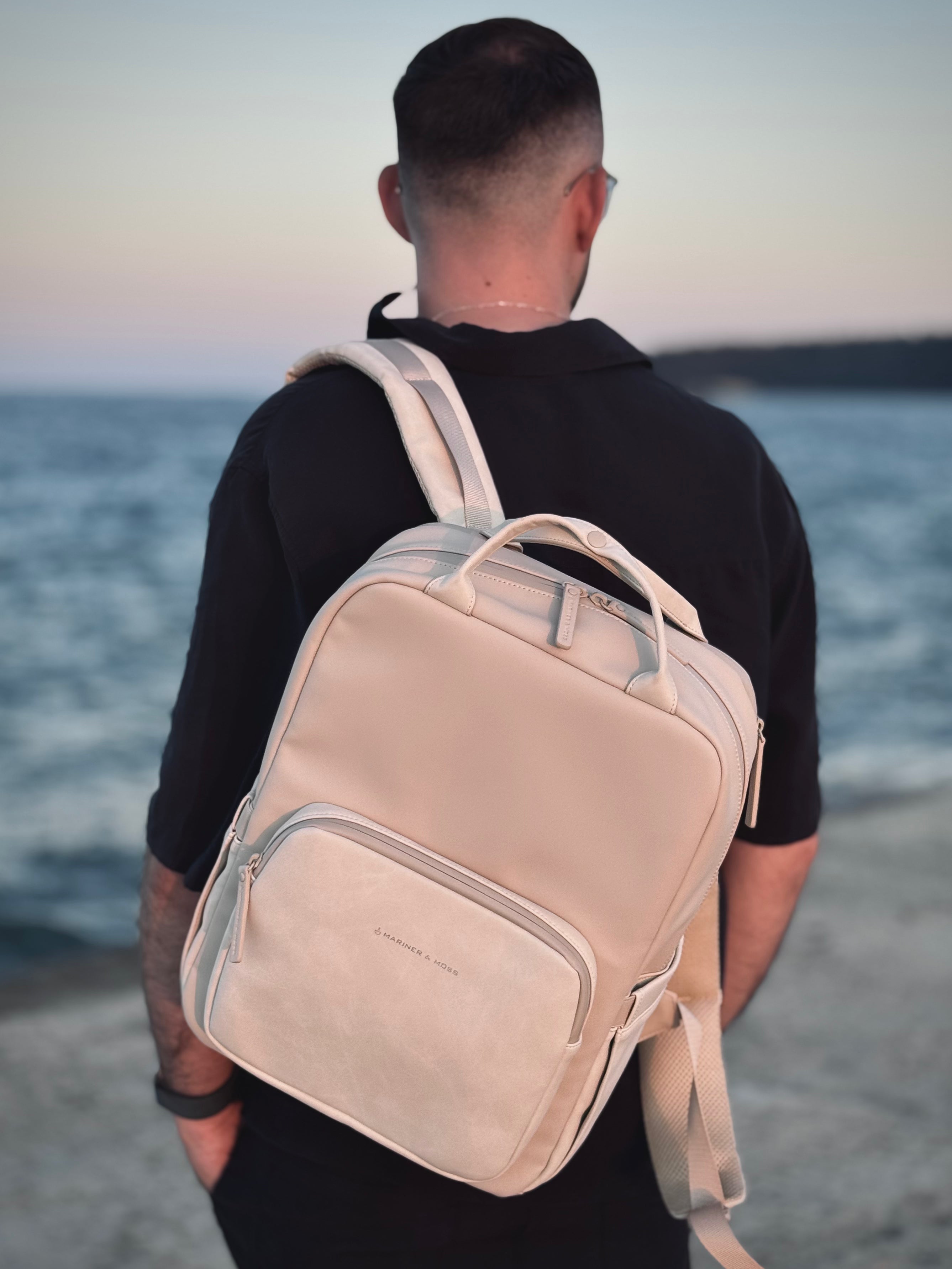 Person wearing a beige backpack on a beach with ocean view